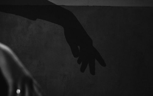 Free Black and white shadow of a hand on a textured wall, creating intrigue. Stock Photo