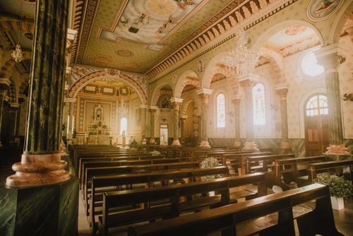 Free Beautifully lit and ornately decorated interior of a historic church showcasing benches and stained glass windows. Stock Photo
