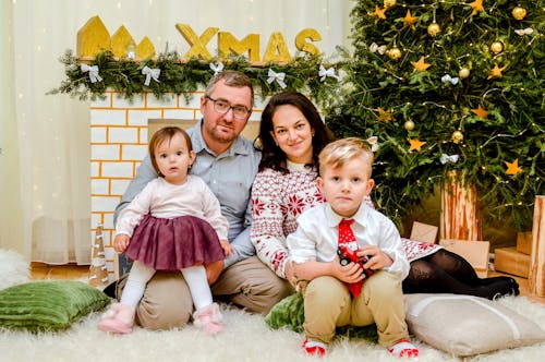 A Family Sitting Together Beside the Christmas Tree