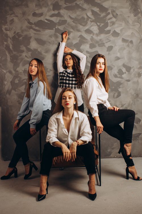 Free Four women striking stylish poses in a studio setting, showcasing fashion. Stock Photo