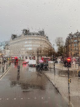 Rainy view through a window in central London capturing the city's bustling street scene and iconic architecture.