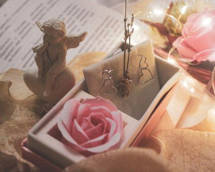 Delicate angel figurine with pink rose and earrings creating a romantic atmosphere in Tashkent.