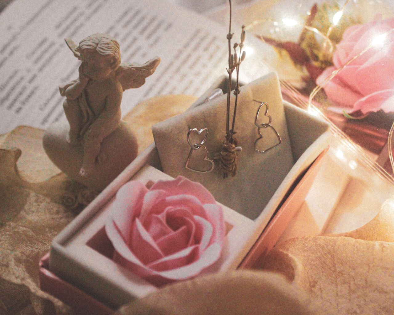 delicate angel figurine with pink rose and earrings creating a romanti