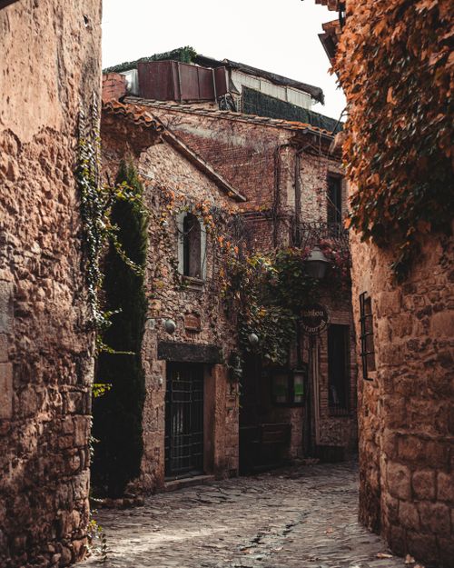 Free Picturesque narrow alley with rustic brick houses in Girona, Spain, showcasing vintage charm. Stock Photo