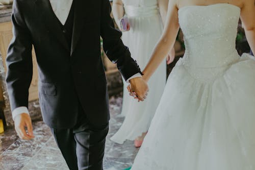 Kobieta Ubrana W Białą Suknię ślubną Trzymając Się Za Ręce Z Człowiekiem Podczas Chodzenia