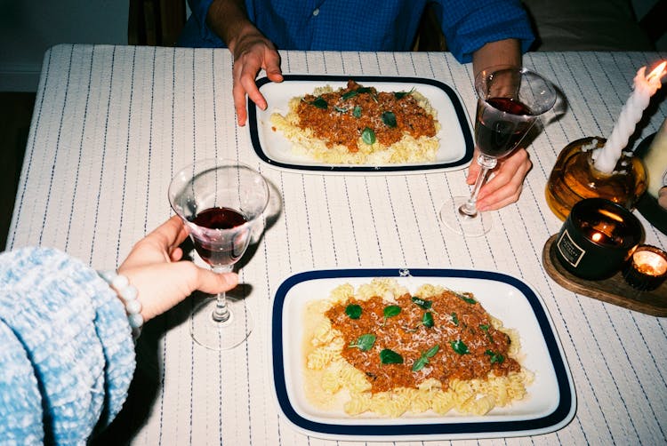 People At Table Eating Pasta And Wine