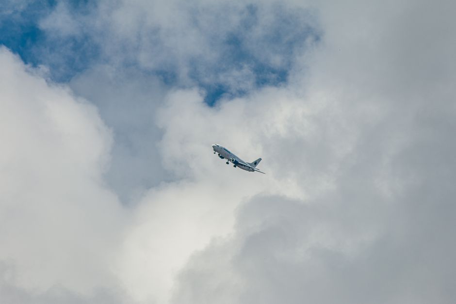A large commercial airplane navigating through white fluffy clouds against a blue sky.