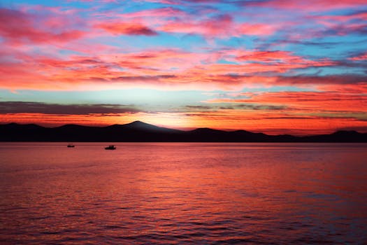 Vibrant sunset with colorful clouds reflecting on serene ocean waters, creating a tranquil seascape.