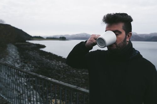 Free A man drinks from a mug by a scenic Scottish lake during winter, capturing a serene moment. Stock Photo