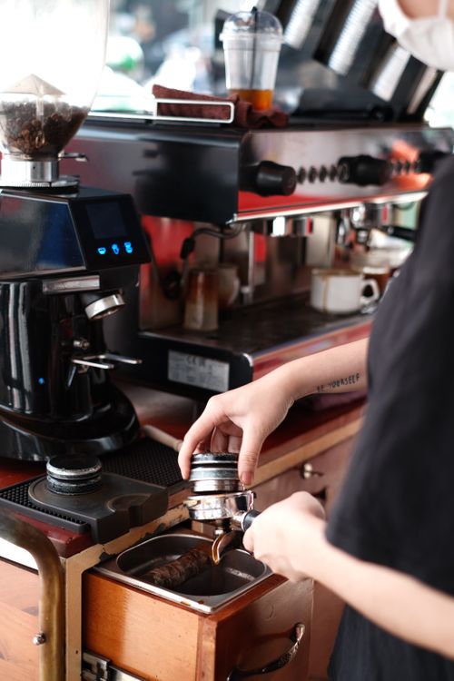 Free Barista preparing coffee using a professional espresso machine in a café. Stock Photo