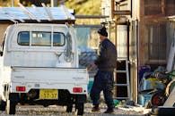 Man in Brown Jacket Standing Beside White Van