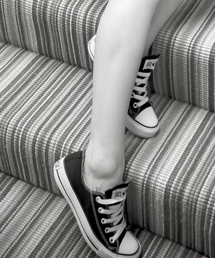 Grayscale Photo Of A Person Wearing Black And White Sneakers Shoes