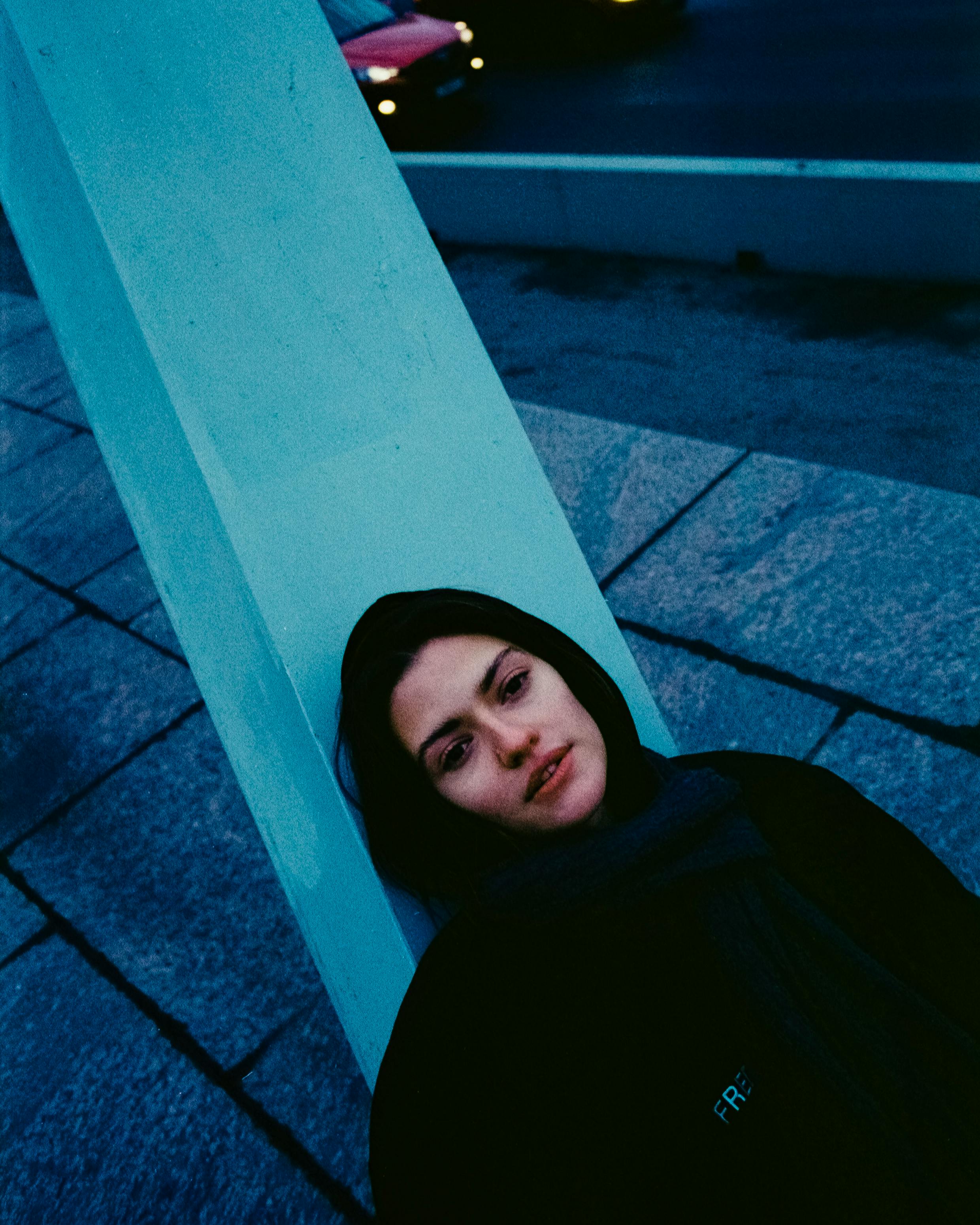 Moody urban portrait of a woman lying against a structure in Saint Petersburg.