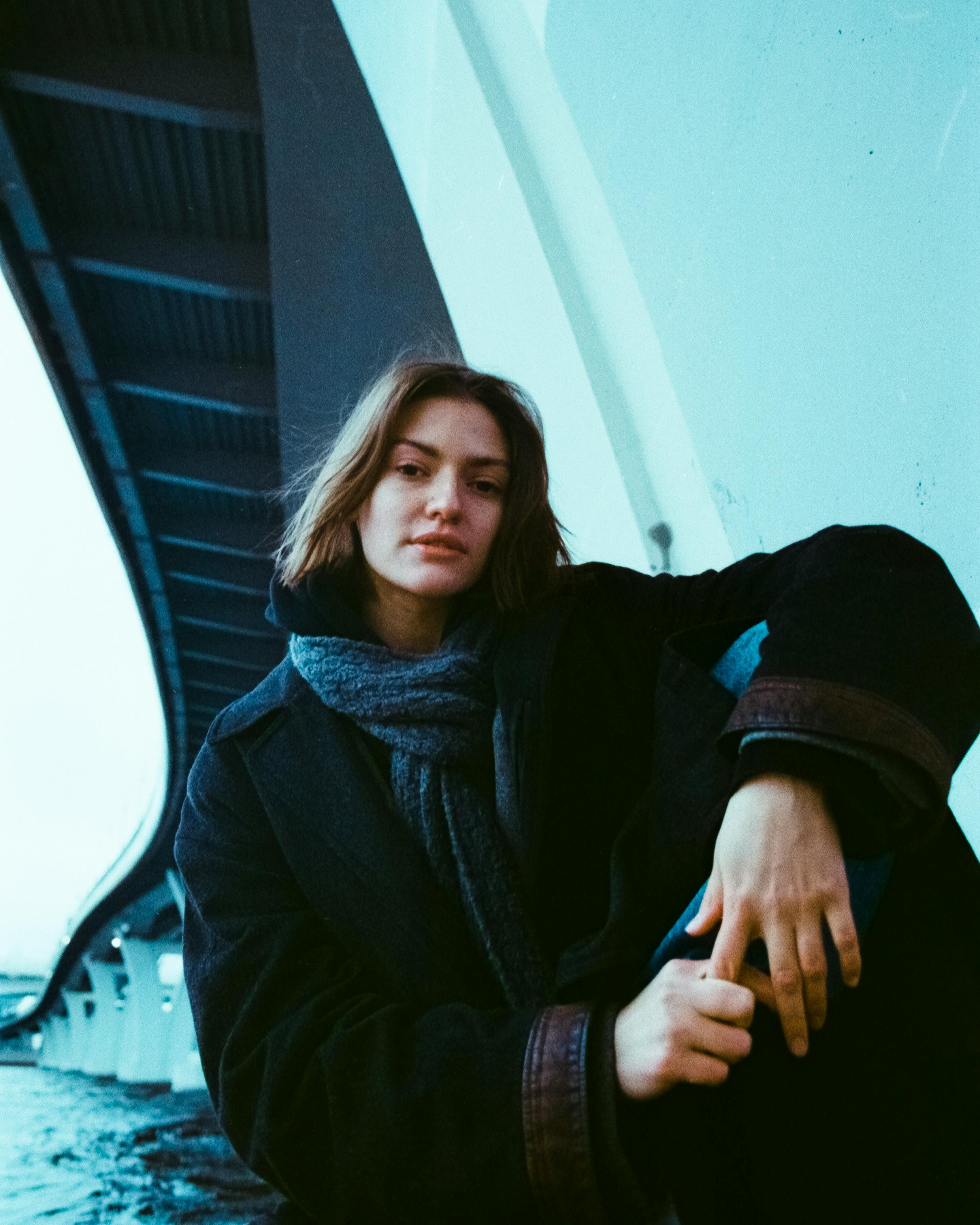 Moody portrait of a woman standing outdoors in winter under a bridge in Saint Petersburg, Russia.