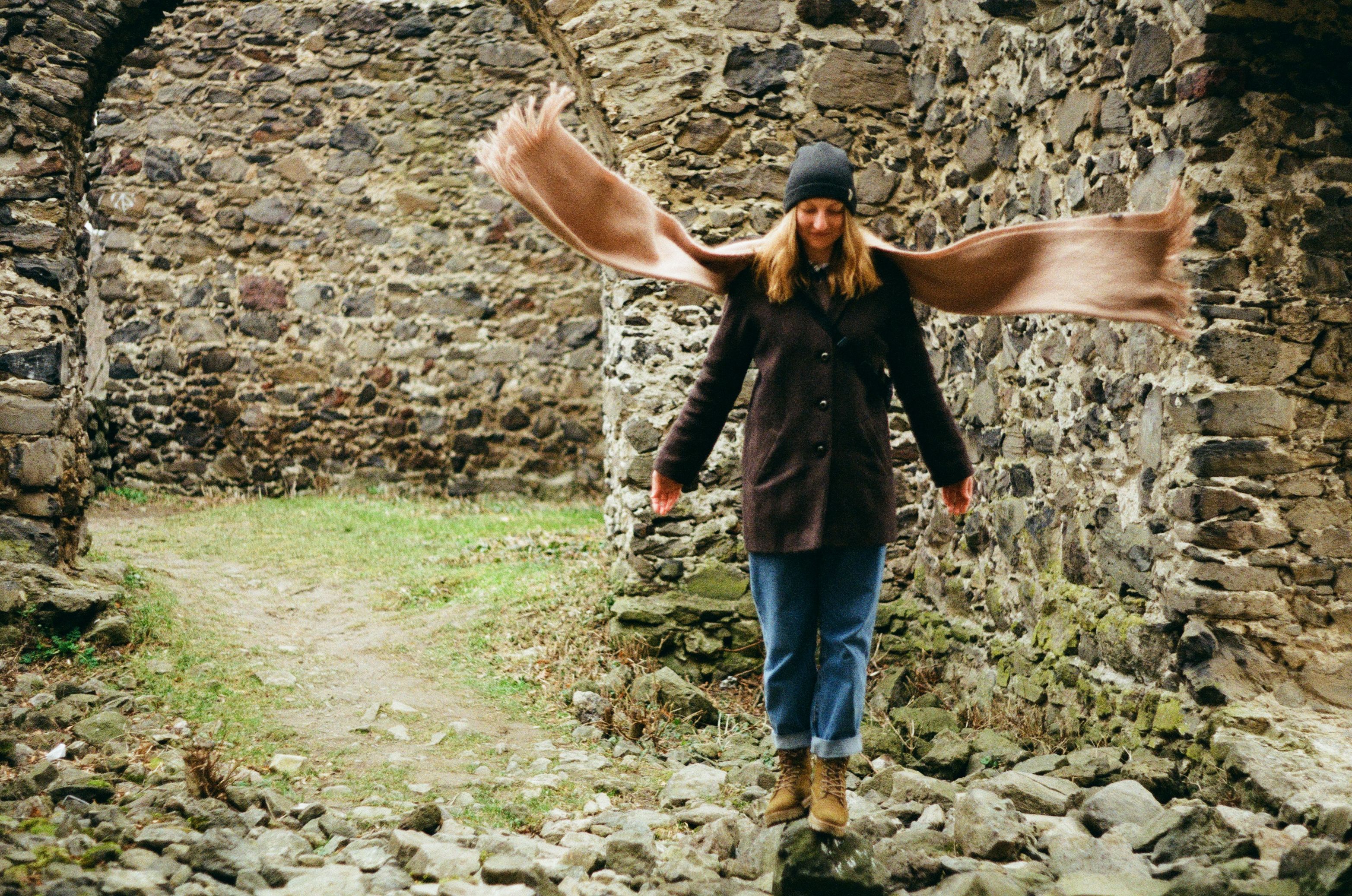 Woman in Brown Coat Walking on Rocks · Free Stock Photo