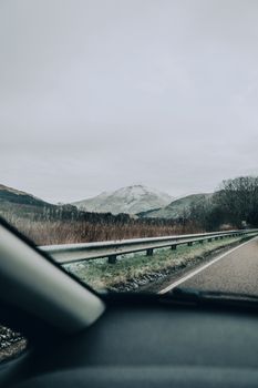 View through car windshield of Scotland’s mountainous landscape and winding road.