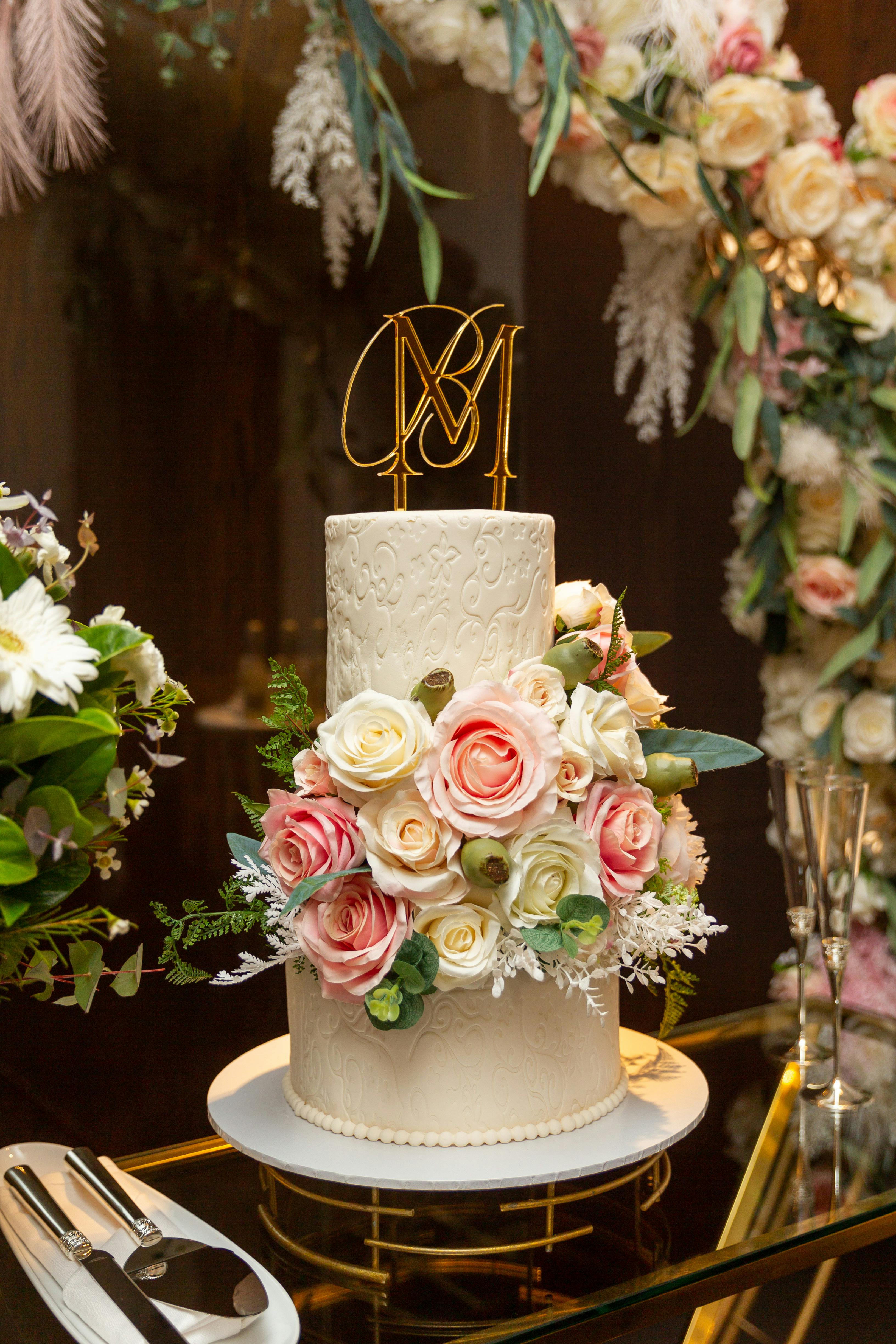 Stunning two-tier white wedding cake adorned with roses, perfect for elegant celebrations.