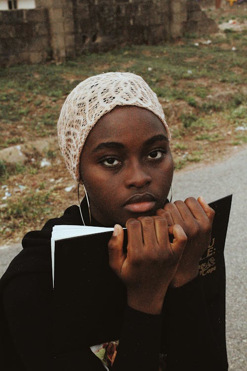 Woman Holding Book and Looking at Camera