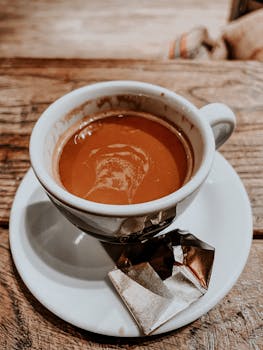 Steaming espresso in a white cup on a wooden table, perfect for coffee lovers.