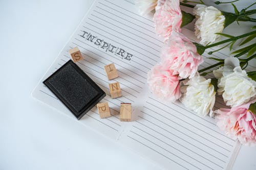 Free Wooden Stamps on Notebook Near Flowers Stock Photo