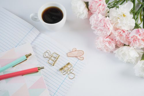 Free A stylish workspace with coffee, flowers, stationery, and notes. Stock Photo