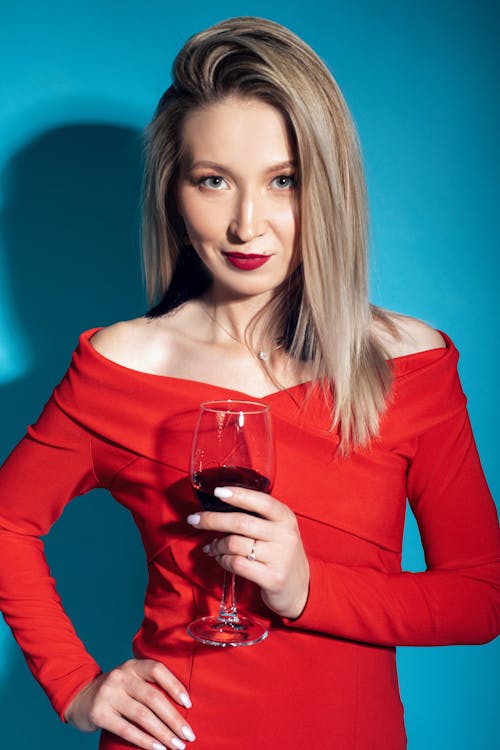A Woman Holding a Glass of Wine while Posing at the Camera