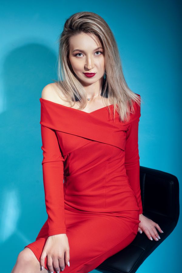 Model in a red dress against a blue studio backdrop — Konstantin Mishchenko on Pexels