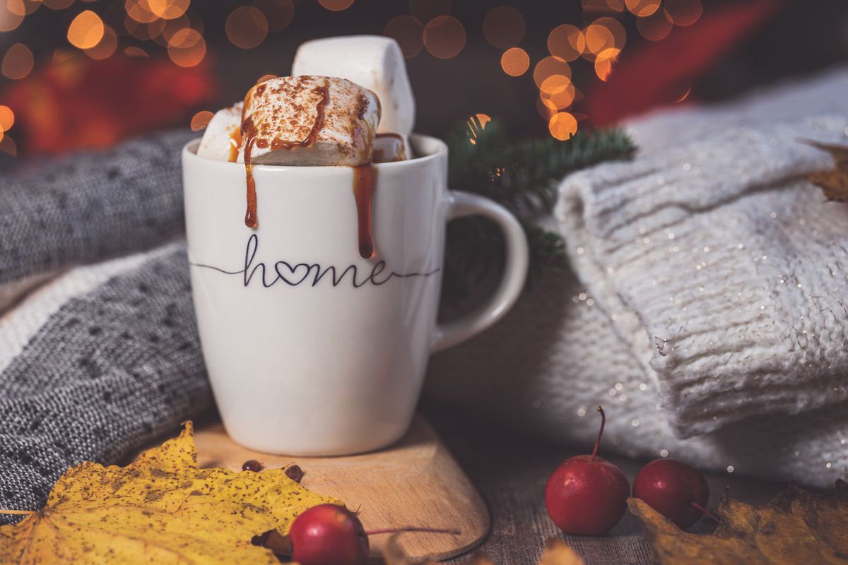 Warm autumn setting with a mug of hot drink, marshmallows, and cozy knitwear.