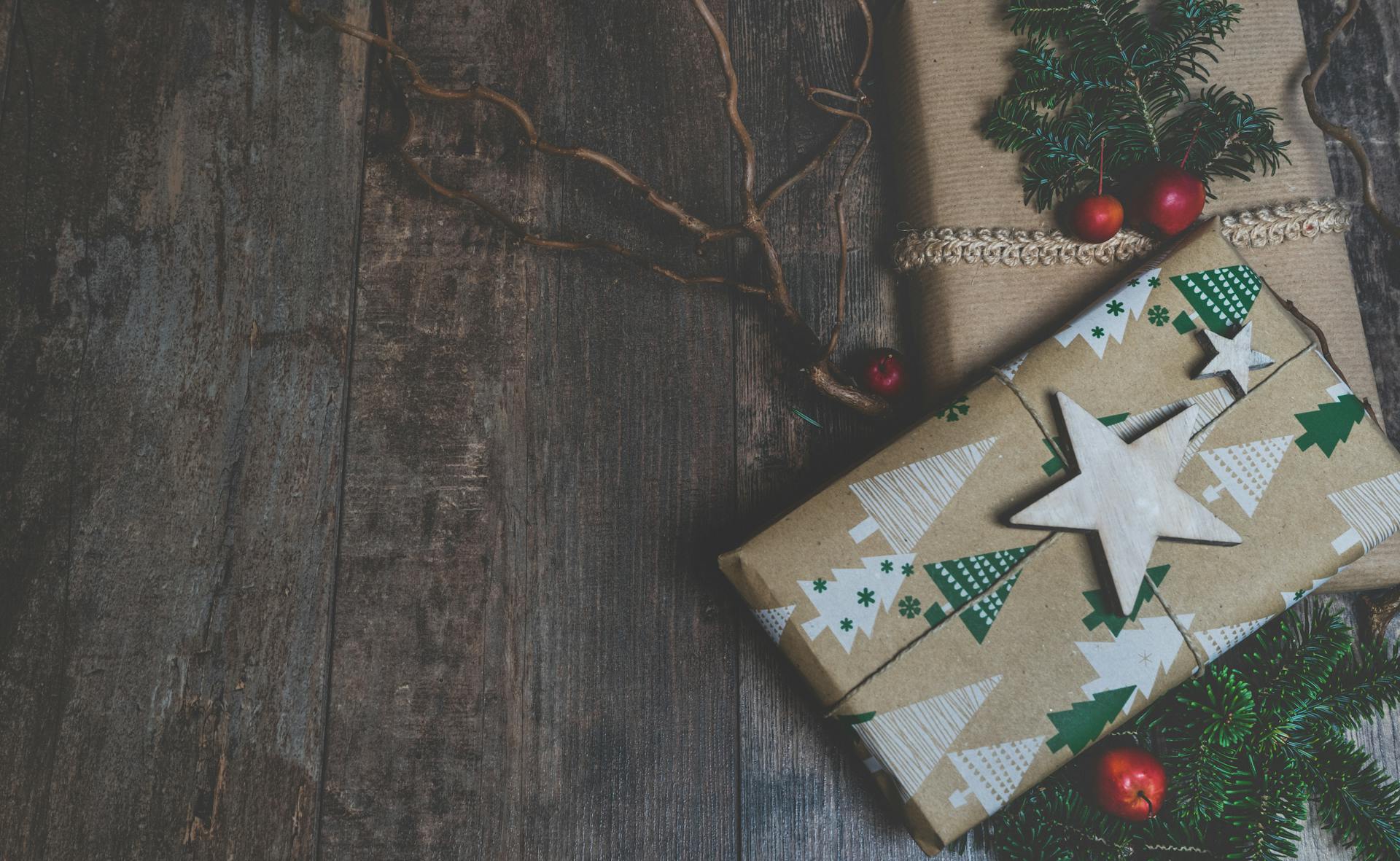 Festive Christmas gift wrapped in tree-patterned paper placed on a rustic wooden surface.