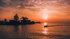 Silhouette of House and Trees by Water during Golden Hour