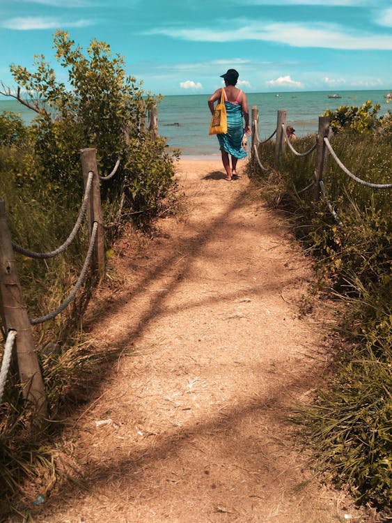 Woman Wearing Blue Scarf Walking on Pathway