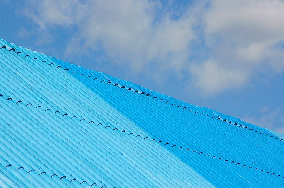 A bright blue corrugated roof shot from a low angle against a clear sky.