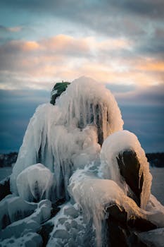 Majestic icy rock formations in winter with a vivid sunset backdrop.