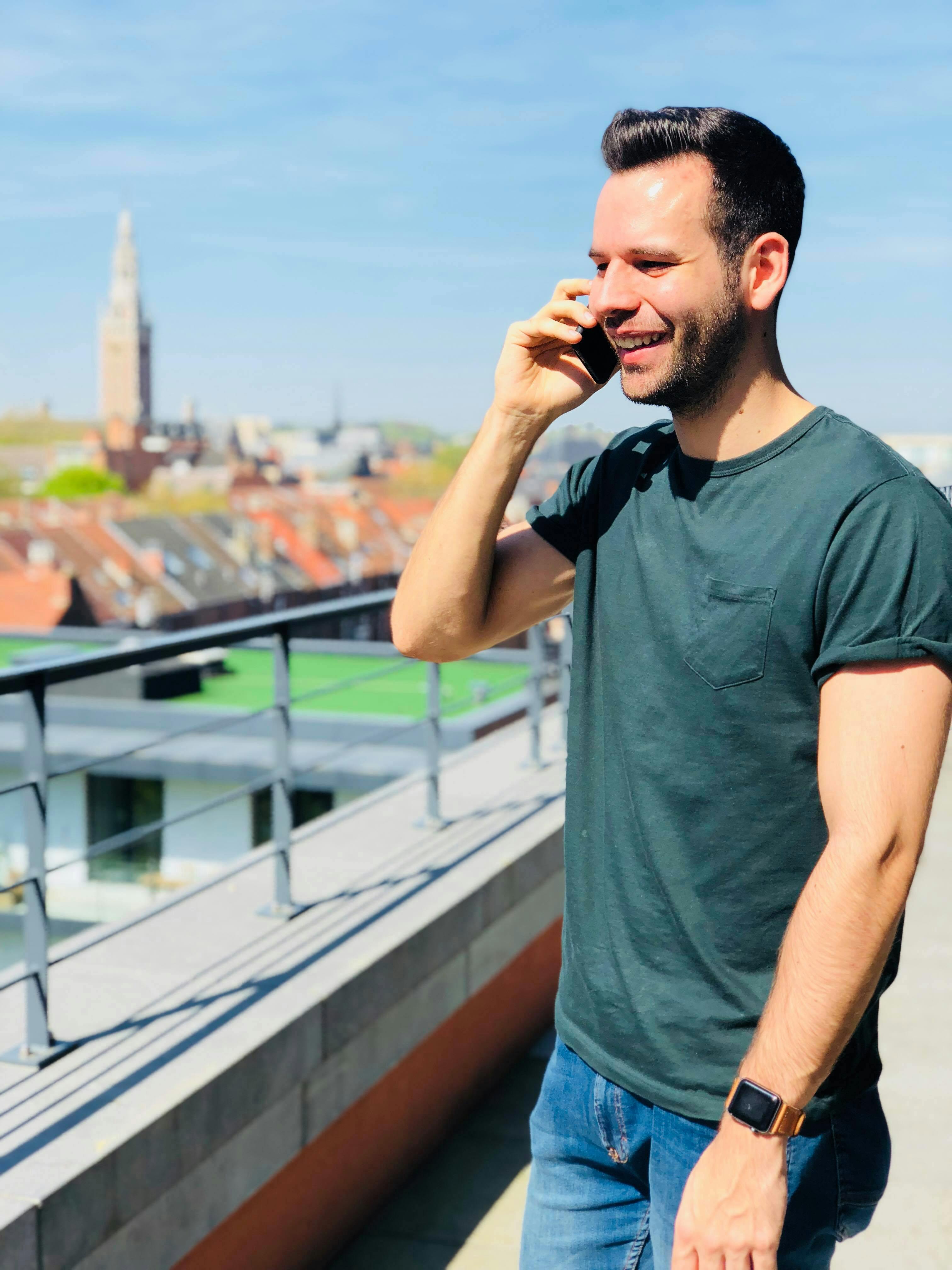 一名男子正在城市景观的背景下，于户外休闲地打电话