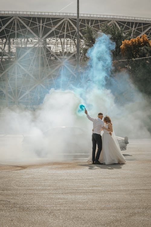 A Groom Holding a Smoke Bomb while Hugging Her Wife