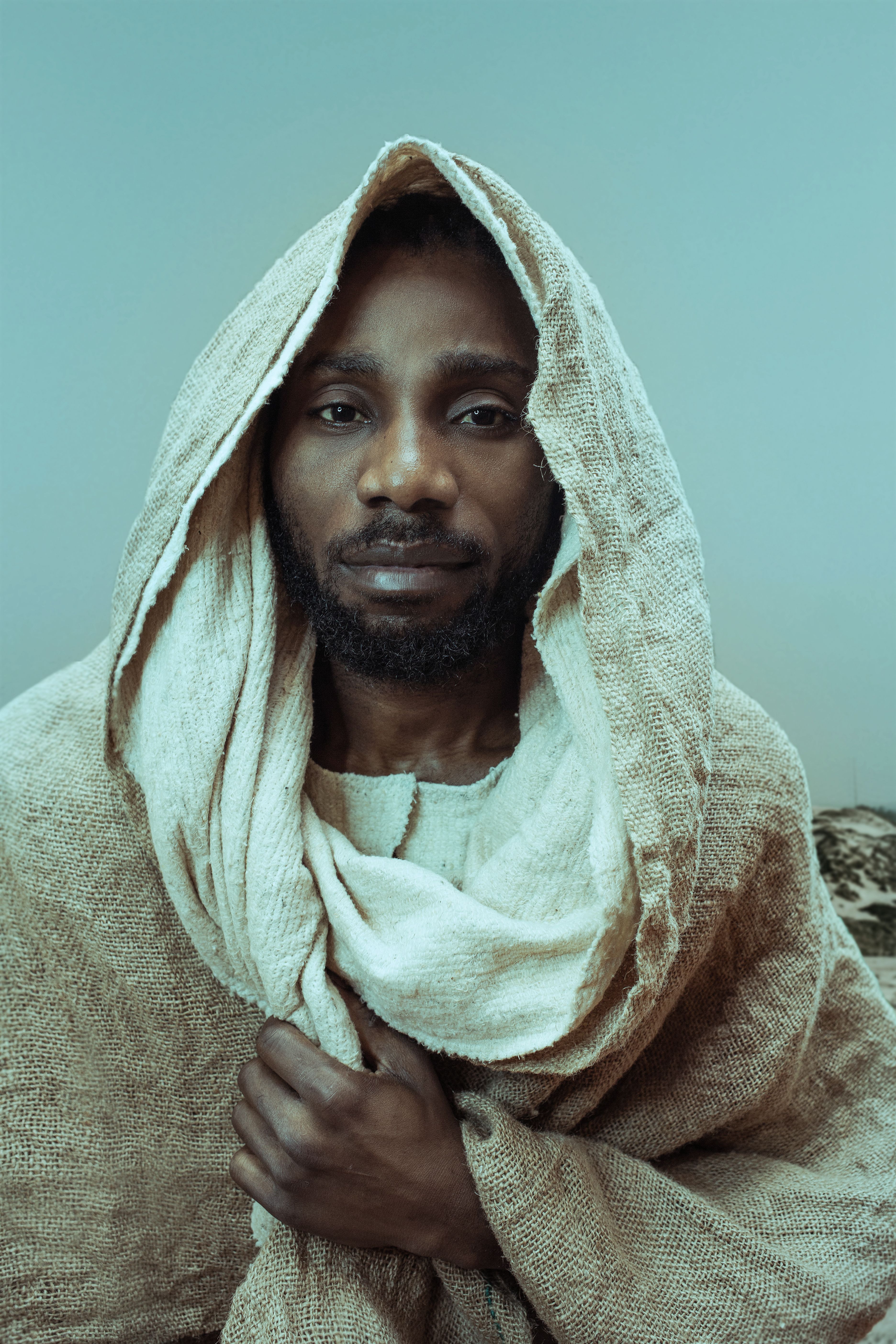 A contemplative portrait of a man wearing an earth-toned headscarf, indoors, with a serene expression.