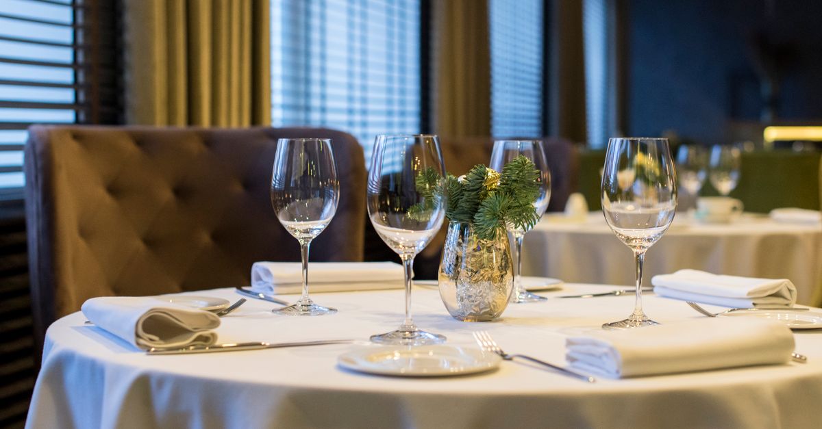 Sophisticated dining setup with polished wine glasses, white napkins, and a decorative centerpiece on a round table.