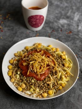 Savor the flavors of Koshari, a traditional Egyptian dish with lentils, chickpeas, and tangy tomato sauce.