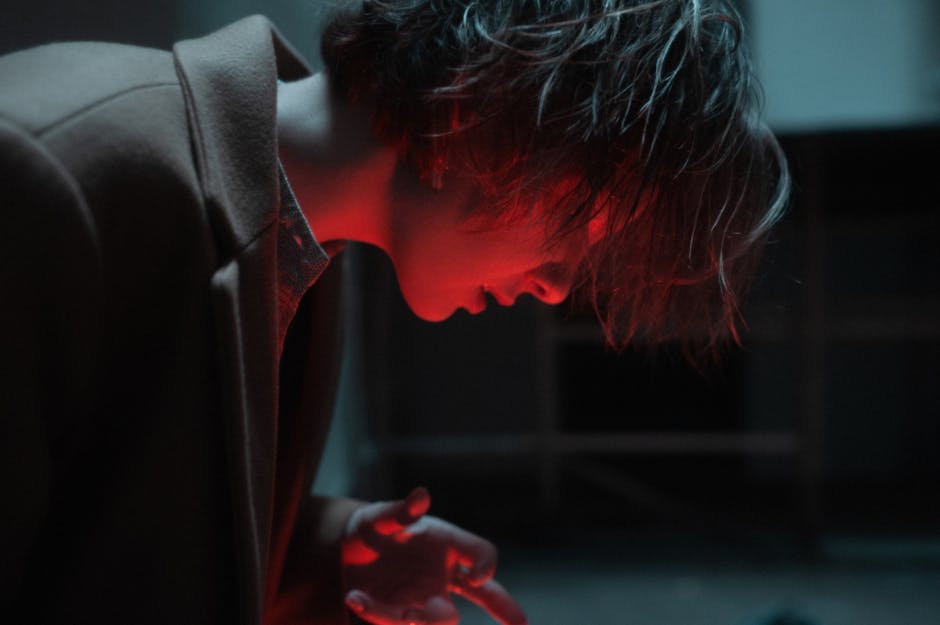 Close-up side view of person illuminated by red light, creating a mysterious ambiance.