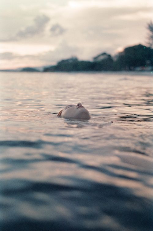 Free Peaceful moment of a woman swimming amidst tranquil waters during a beautiful sunset. Stock Photo
