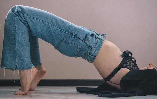 Woman in denim and lace lingerie showcasing flexibility in a studio fashion shoot.