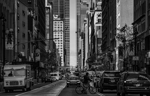 Free Grayscale Photo of a Person Crossing the Street with a Bicycle Stock Photo