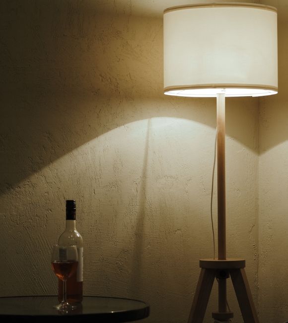 Warm ambient lighting with a wine bottle and glass on a table next to a floor lamp.