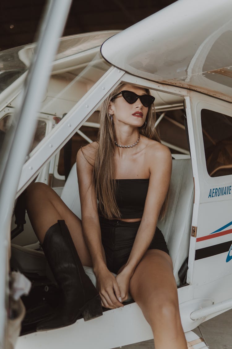 A Woman In A Stylish Outfit Sitting An Airplane