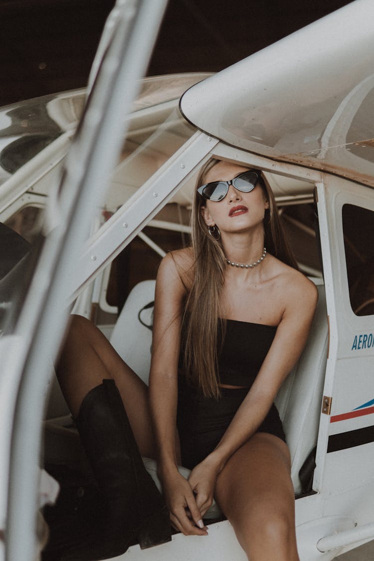 A Woman In A Stylish Outfit Sitting An Airplane