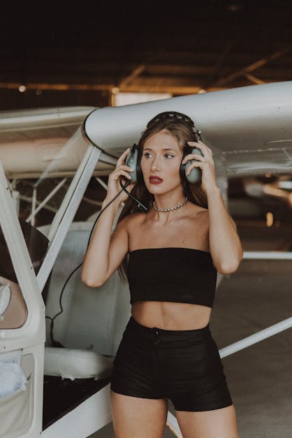 Woman in Black Tube Top Wearing Headset Beside an Airplane