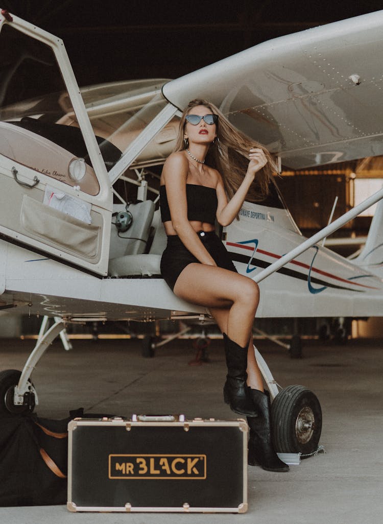 A Woman In A Stylish Outfit Sitting On An Airplane