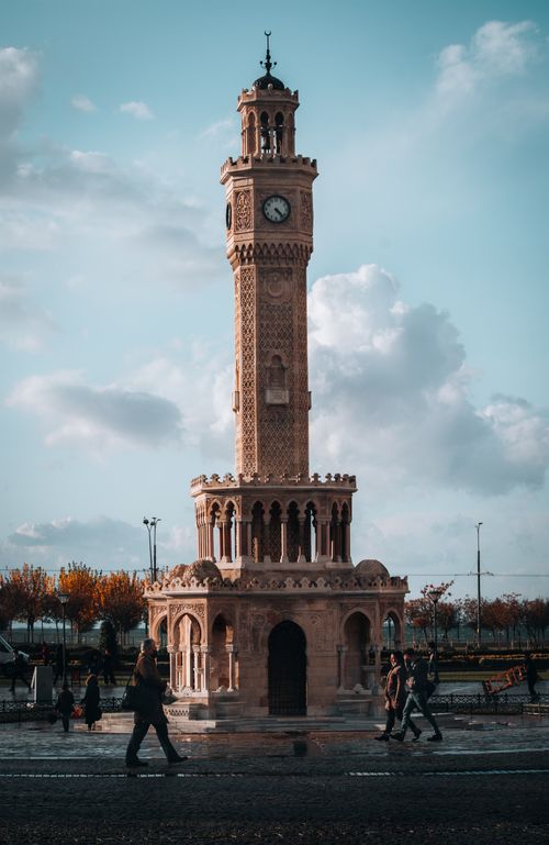 Free A view of the historical İzmir Clock Tower with people walking by, captured on a cloudy day. Stock Photo