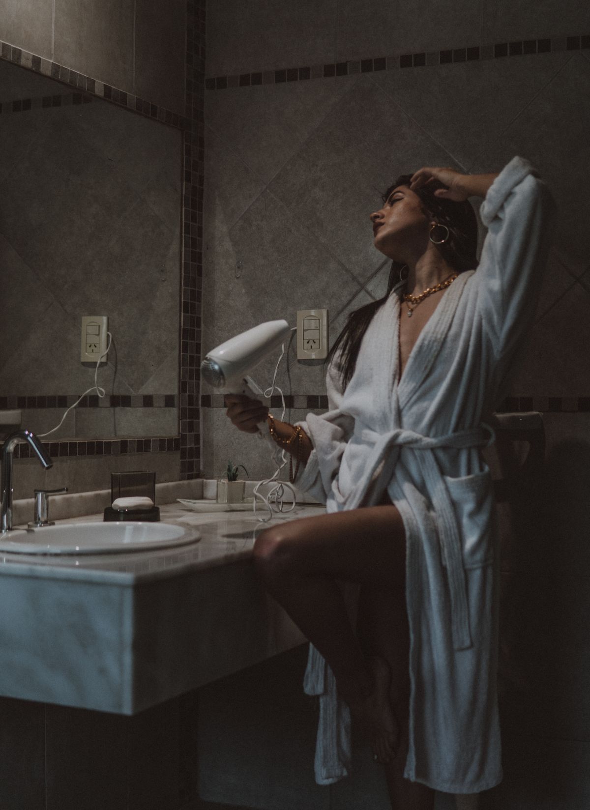 Woman styling her hair with a hair dryer in a bathroom