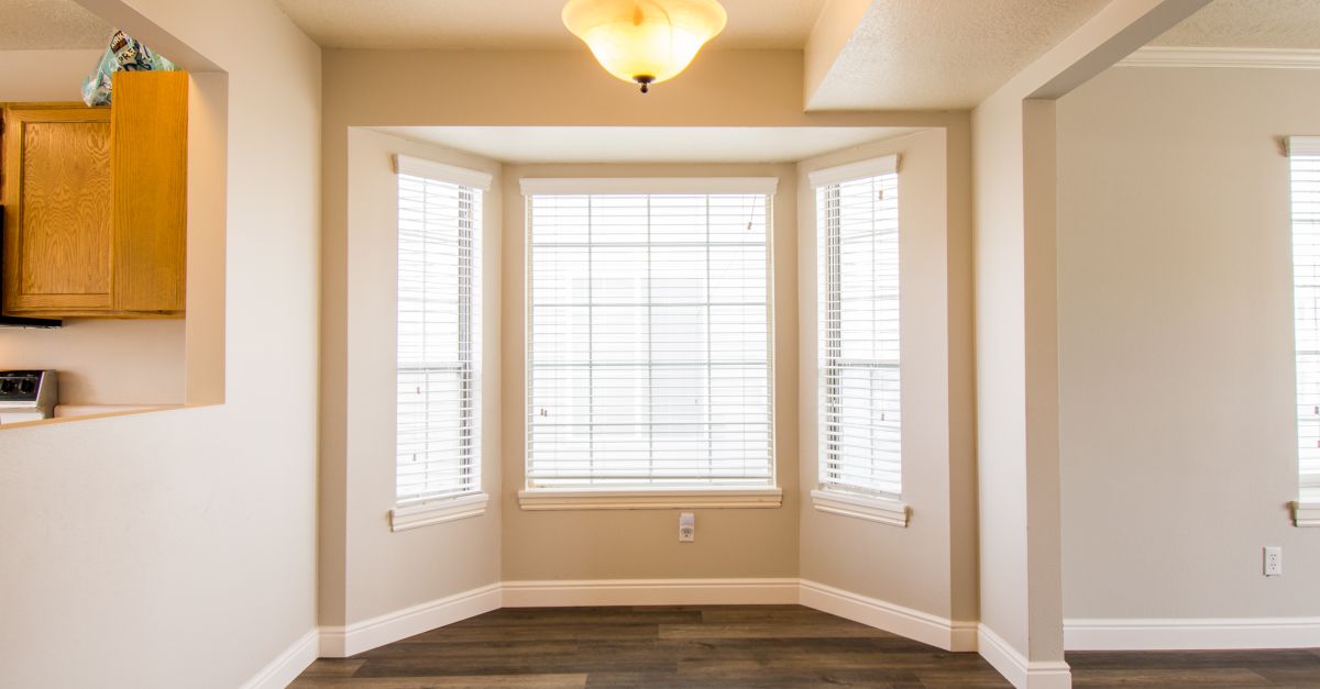 A bright and spacious minimalist interior with large bay windows and modern lighting.